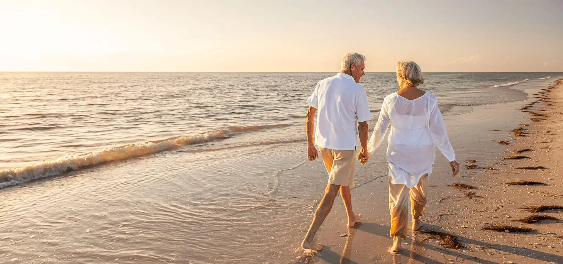 Senior couple strolling hand-in-hand at sunset