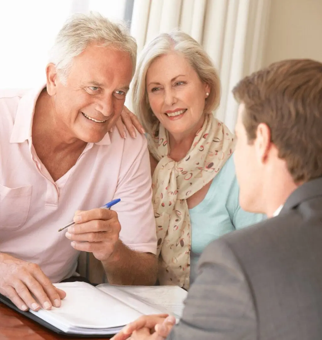 Smiling senior couple reviewing paperwork with advisor